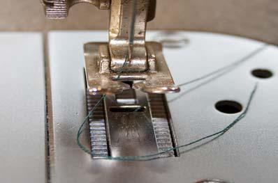 Take one hand guided stitch in two of the button s holes to hold it in place without lowering the presser foot.