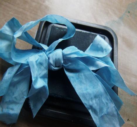 Scrunch a bow made out the blue Limoges vintage ribbon into the ink & work it around. Step 21.