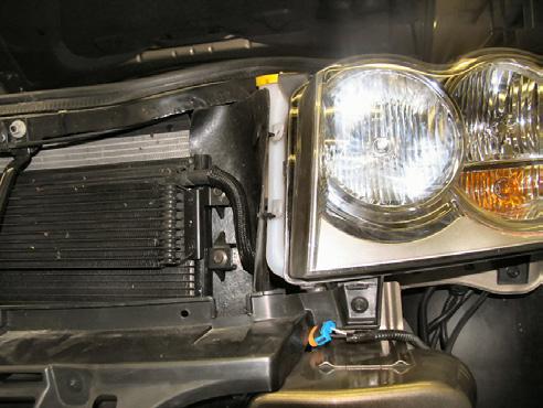 Remove two (2) christmas tree pushpins from the washer reservoir spout and air dam just inside of the headlight