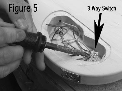 While still holding the switch in place turn the body over and slip the washer onto the protruding shaft and loosely screw on the nut. Look at the switch mechanism inside the cavity.