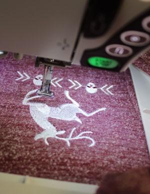 Once your design is hooped up under your machine, and your machine centered over your design, you can get stitching!