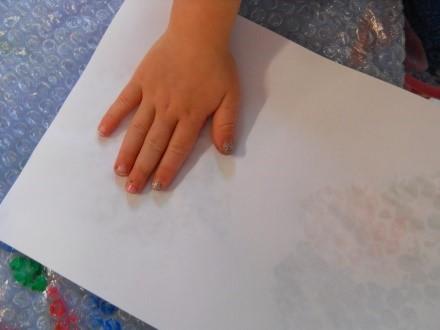 The child places a sheet of paper over the painting and gently rubs over