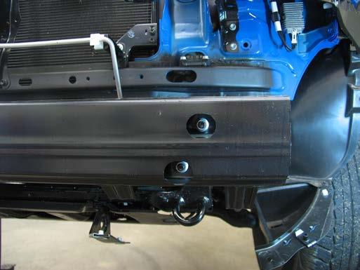 7. Using the 10MM socket, remove two metric bolts from the bottom edge of the fascia, just forward of the radiator.