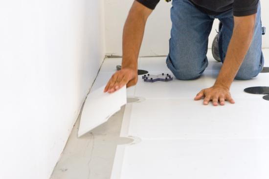 Temporarily cover the exposed Hook Plates with a suitable material (e.g. cardboard that is taped to the concrete floor on one side and to the wood surface on the other side).