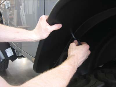 Slide the tool along the edge trim while pressing it in toward the vehicle surface.