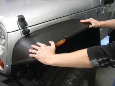 Push down lightly on the fender fl are to create a small gap between the sheet metal and the edge trim.