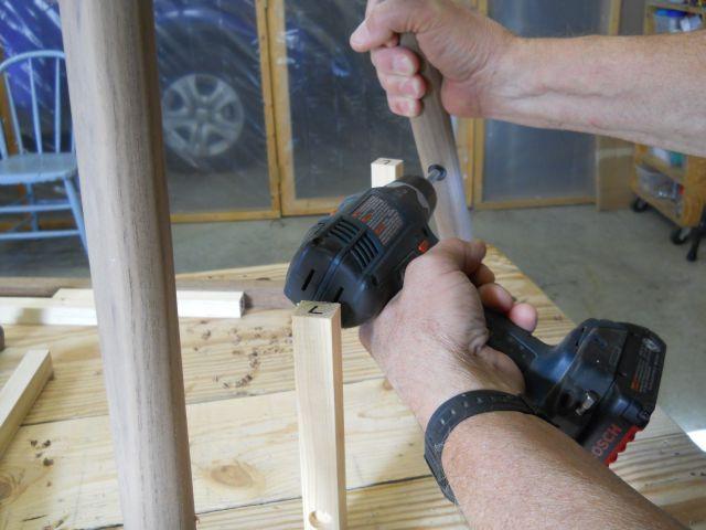 Drilling pocket mortise for stretcher end; block used to assist with vertical alignment of mortise: Determine the three stretcher lengths needed by measuring the distance between tenon mortise