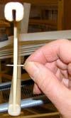 Start in the center of the heddle. Select 6 or 8 yarns and stroke them to straighten them. Divide them in the middle into two parts, half on the right and half on the left.