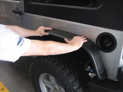 Push down lightly on the fender fl are to create a small gap between the sheet metal and the edge trim.