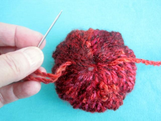 Add a Hanger and Embellishments With your tapestry needle, sew a 6 to 8 inch length of yarn across the top
