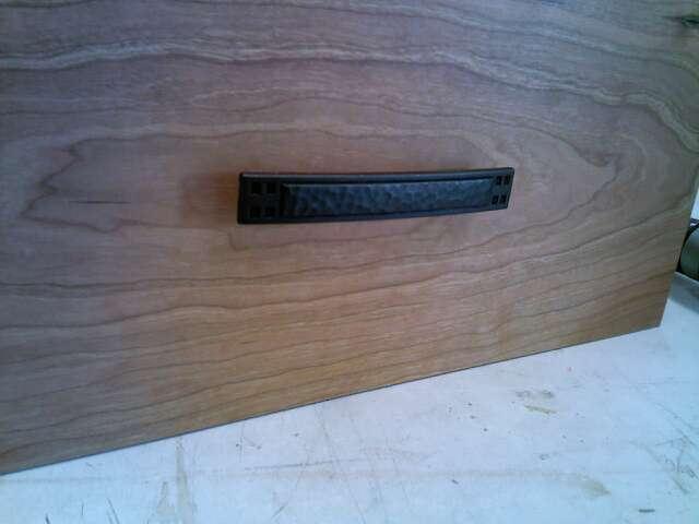 This hardware is mounted through the drawer fronts and door stiles with screws.