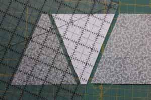Rotate the ruler so the bottom of the triangle is aligned with the top of the fabric and the cut edge matches the angle of the