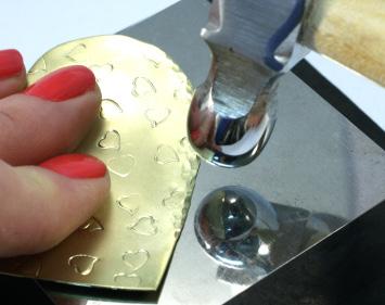 Step 4 Using the small, back end of your chasing hammer, tap just along the outside edge of the brass heart shape.