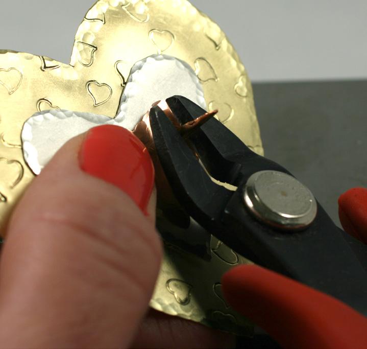 After the silver heart has been punched, use it to mark the brass heart for punching. Stack the three hearts to check the alignment of the holes.