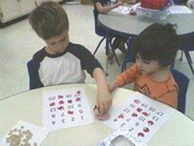 One partner show a number card and the other collects that number of objects.