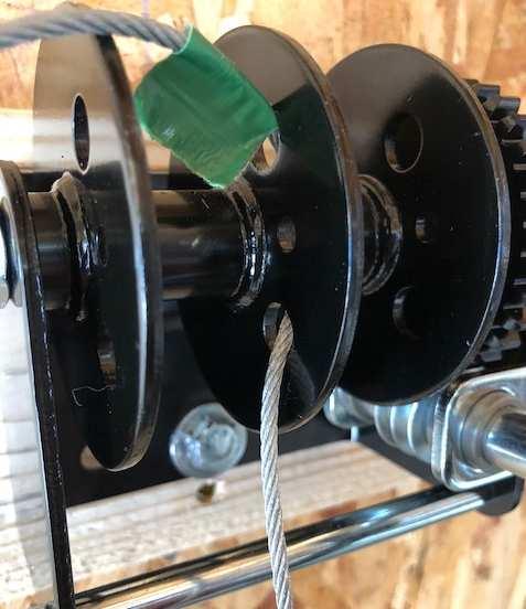 2. Starting with the marked end of the tape (20 side) insert the cable into one of the larger holes on the spool of the crank assembly from left