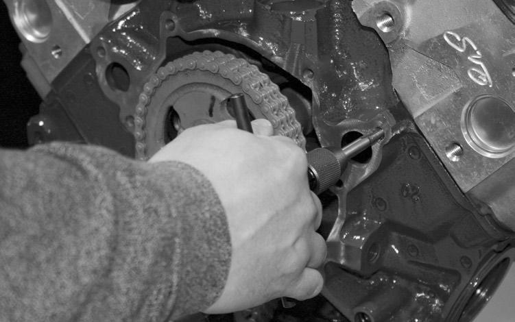 First Cut the exposed oil pan gasket flush with engine block using a sharp blade, then remove the first three bolts from the oil pan on each side and loosen the